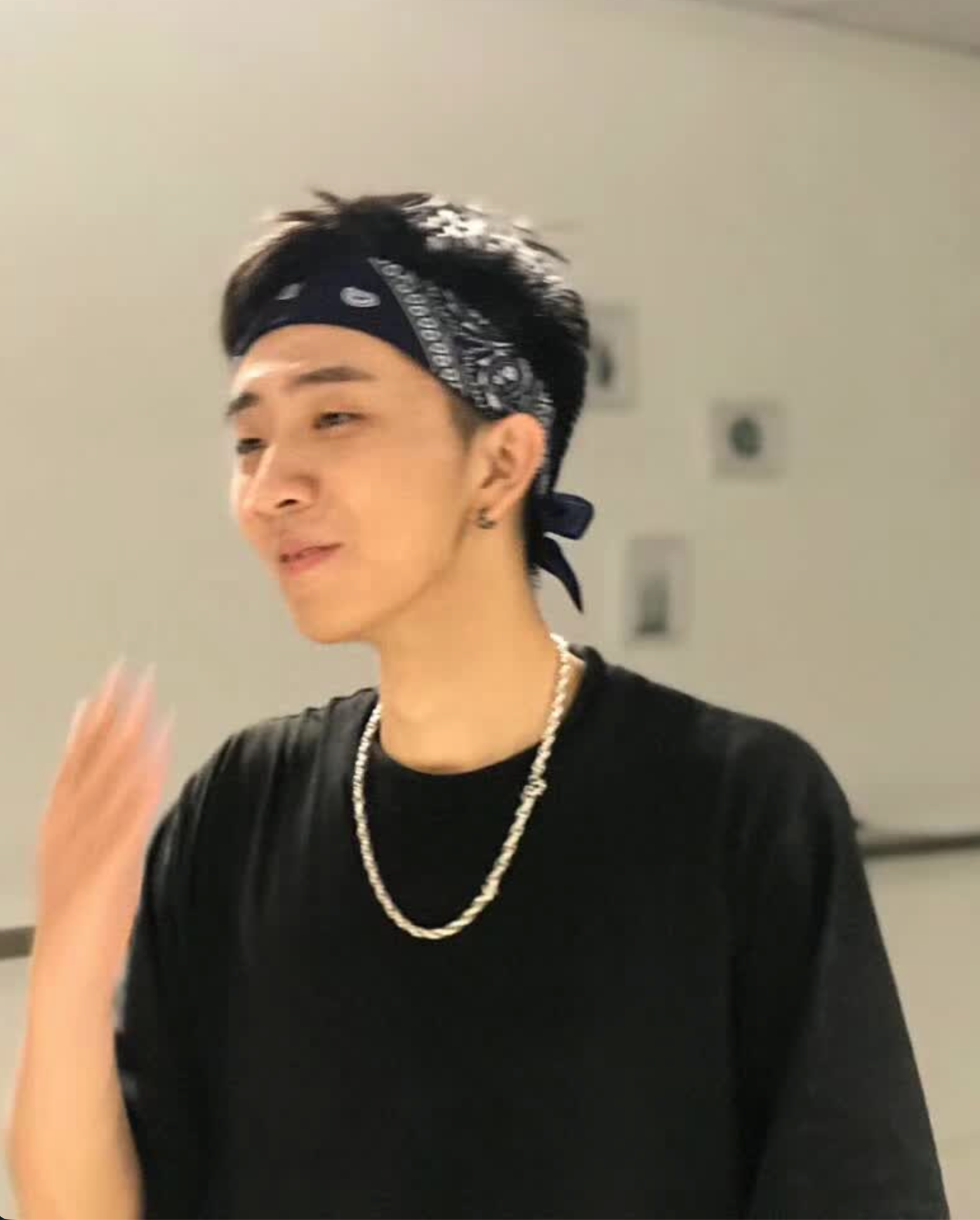 A person wearing a black bandana and T-shirt during dance practice.