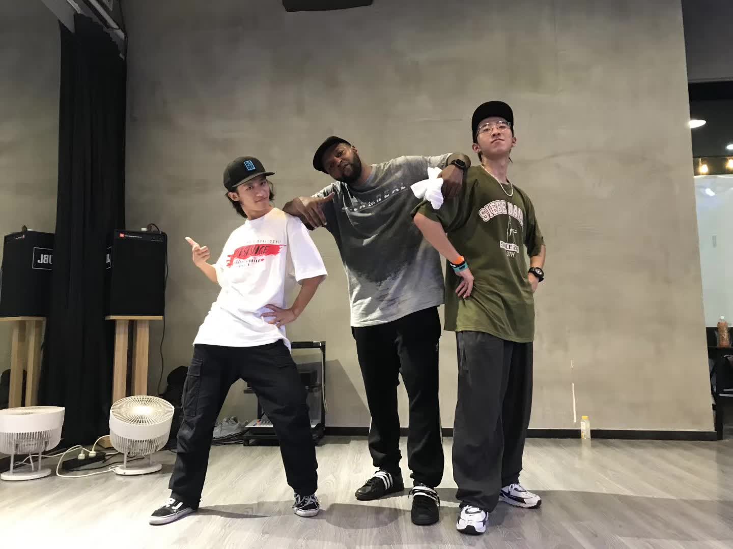 Three people posing together in a dance studio.