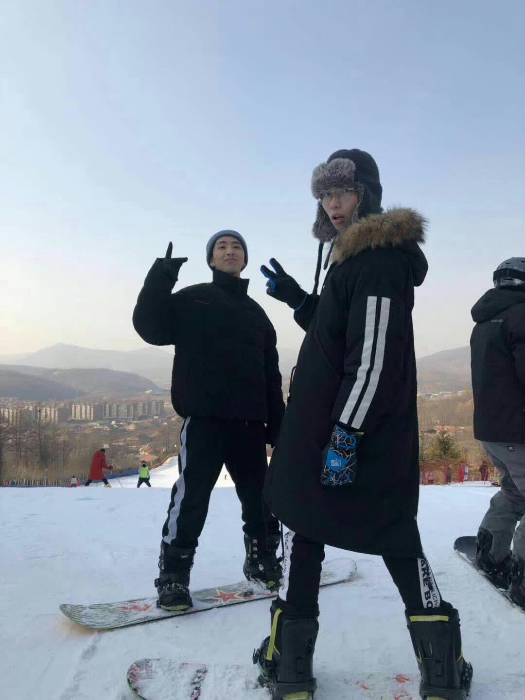 Two snowboarders posing on a snowy slope with mountains in the background.