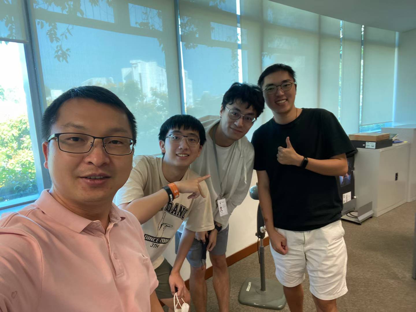 Four people posing together for a group selfie in a bright office.