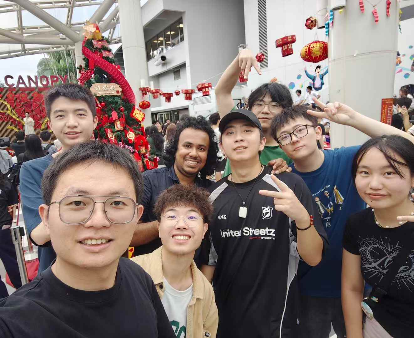 A group selfie at an indoor event with red festive decorations.