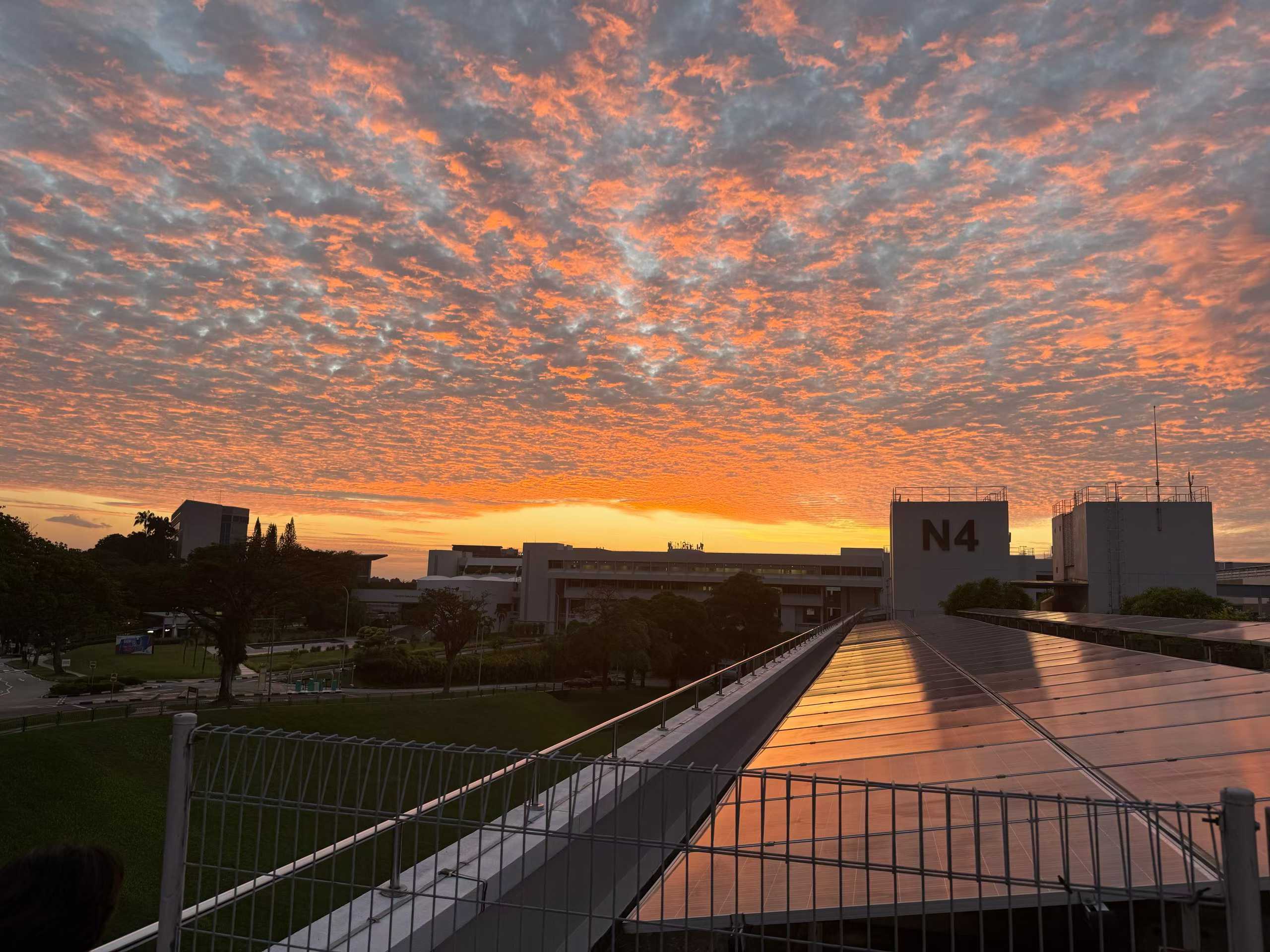 Orange sunset clouds above NTU campus buildings and rooftops.